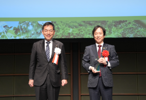 浅尾環境大臣（左）とトロフィーを持つ隅野社長